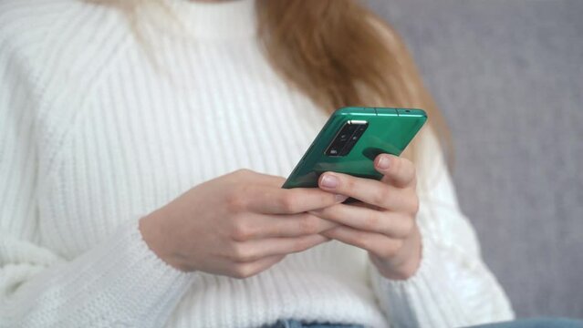 Close-up of beautiful female hands with phone. Typing message on modern smartphone