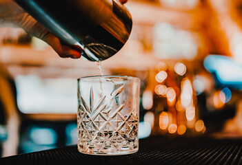 woman bartender hand making negroni cocktail. Negroni classic cocktail and gin short drink with sweet vermouth, red bitter liqueur