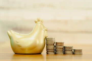Gold chicken bank with coins stacking placed on the side, saving money wealth and financial concept