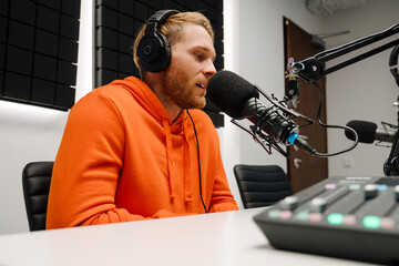 Happy young male radio host broadcasting in studio