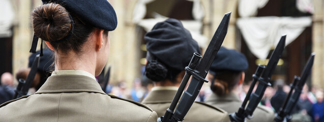 Horizontal banner or header with uniformed women standing during the military ceremony in Bologna, Italy. In the foreground, a woman seen from behind with a bayonet rifle. - obrazy, fototapety, plakaty