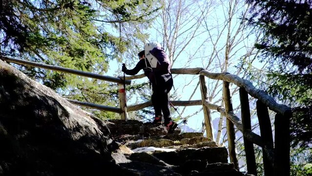 Donna con zaino sale un sentiero tra le foreste in Val di Mello, Valtellina, Italia