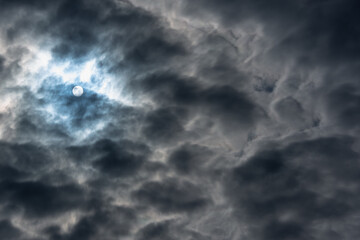 Obraz premium Sun behind thick clouds before storm and rain.
