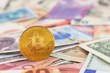 Close-up Golden Bitcoin coin on blurred currency banknotes background. Financial background with world currency money banknotes and cryptocurrency. Selective focus