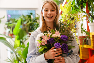 White beautiful florist girl holding bouquet with flowers in shop