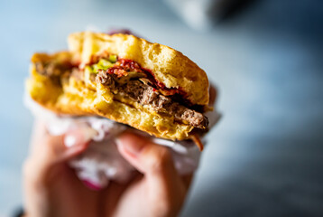 Young woman holding in female hands fast food burger