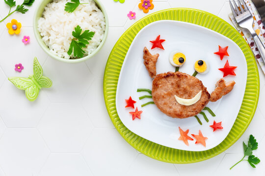Fun Food for Kids - cute smiling crab shaped veal burger juggling with red starfish served with rice for a healthy lunch or dinner