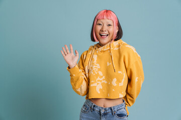Asian girl with pink hair and piercing laughing while waving hand