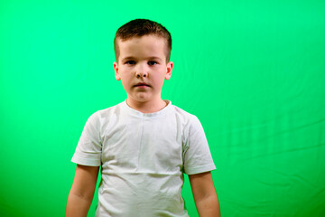 A boy on a green background.angry look