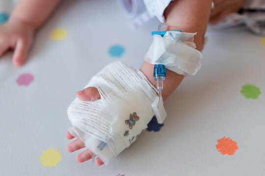 image blur,baby hand with bandage giving saline on bed in hospital.