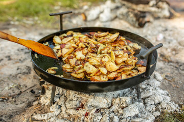 Fried potatoes on a fire in nature in the forest. Concept: vegetables, food, travel