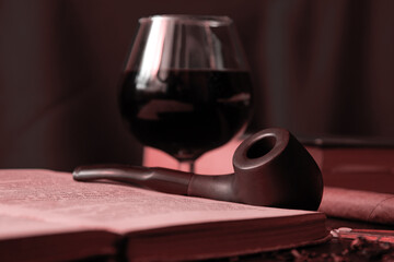 Moody dark image of the reading cabinet with smoking eqip, cognac, books. Classic vintage relaxation concepts