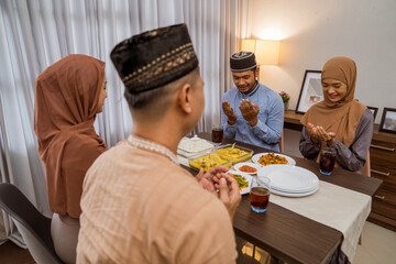 muslim people praying before break fasting iftar dinner together at home in ramadan celebration