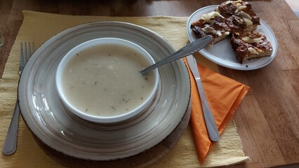 Cremesuppe in einer weißen Porzellanschale. Pilzsuppe in Nahaufnahme. Kartoffelsoße direkt darüber. Das Serviertablett aus Keramik. Retro Stil auf hölzernem Hintergrund. Essen auf dem Tisch. Gesundes.