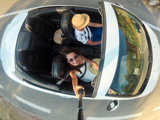 Joyful young woman sitting in a cabriolet and smiling at the camera - Happy couple riding on the...