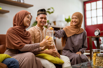 visiting friend and family during eid mubarak islamic day. beautiful of muslim family sitting in livingroom enjoying some snacks served by home owner