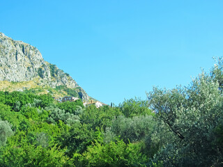 A wall of mountains rises above the valley. Warm tones on a sunny day with a small village in the hills. Mountains rock granite