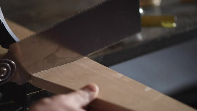 carpenter sawing a workpiece with a Japanese saw