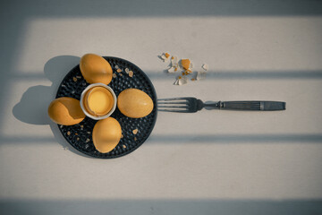 Composition of Broken fresh chicken egg (Hen egg) put at the middle of the fresh eggs with brown eggshell and Black antique silver fork on white table. Natural organic healthy food concept, Top view, 