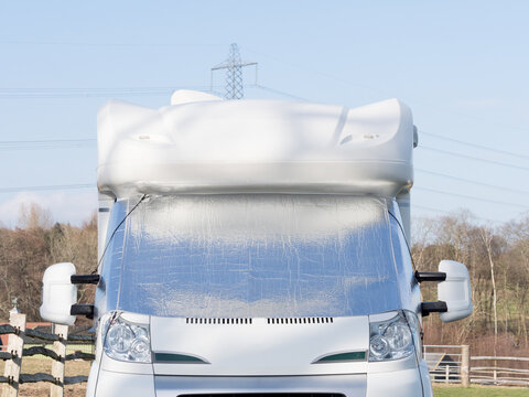 A motorhome recreational vehicle has a silver screen on its windscreen as protection from frost and condensation. Front view
