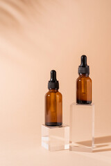 Glass dropper bottles with a pippette with black rubber tip on glass podium and beige background, mockup design