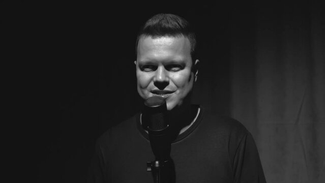 a man gnaws a microphone in a dark recording studio.black and white version.