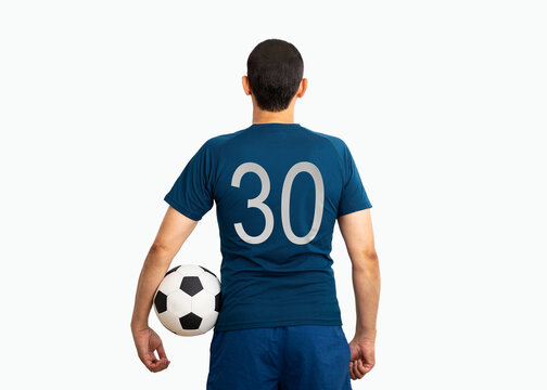 Cropped image and rear view of a young player with number thirty holding a soccer ball under his arms with white background