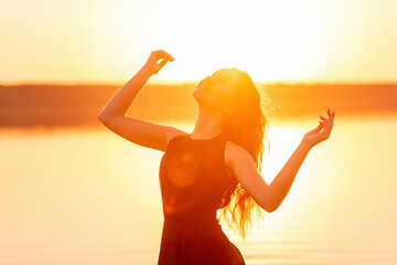 Close-up portrait of silhouette of curly, free girl, wind in her hair, light movements at sunset