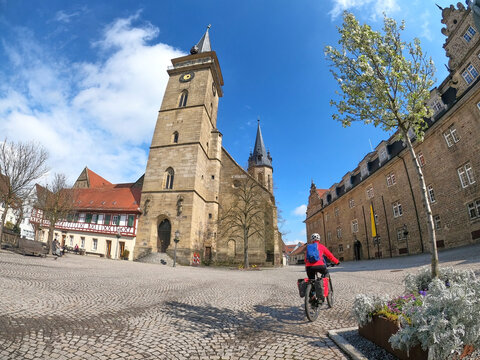 &Ouml;hringen. Baden-Wuerttemberg, Germany, 03-14-2022, woman on bicycle tour in downtown of &Ouml;hringen, with its famous old church and market place