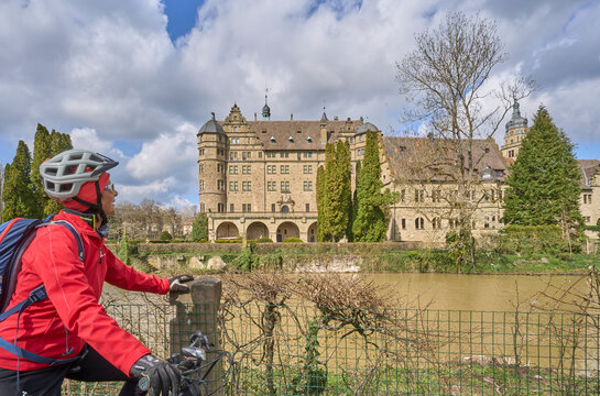 woman on bicycle tour in downtown of Neuenstein am Kocher, with its famous Renaissance  Residence water castle, Baden-Wuerttemberg. Germany