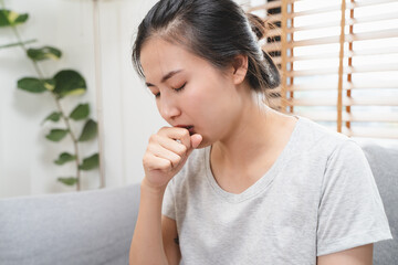 asian woman coughing and feeling sore throat at home.