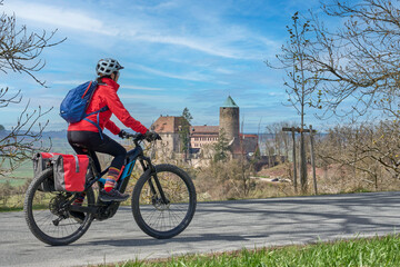 nice city woman on a cycling tour on the famous German route of castles, in front of the medieval castle of Colmberg, Franconia, Bavaria, Germany