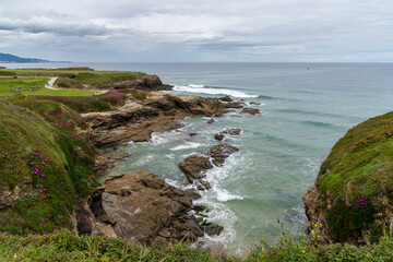 idyllic rocky cove with blossoming flowers on the coast of Galicia with a stone footpath in the background