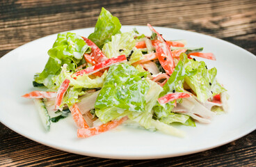 Vegetable salad of lettuce, crab sticks, carrots, filled with yogurt. Bright salad of fresh vegetables. Food background. Vegetarian dish. Side view. Close-up.