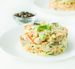 Salad Olivier on a white wooden table. Food background. Vegetarian dish. Side view. Close-up.