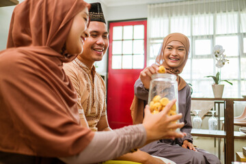 visiting friend and family during eid mubarak islamic day. beautiful of muslim family sitting in livingroom enjoying some snacks served by home owner