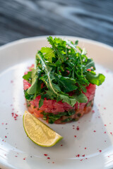 Fresh salmon and tuna tartare with lime and greens on white plate