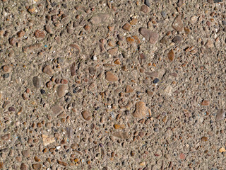 The textural detail of the concrete surface with small gravel pebbles is an abstract background. Multi colored pebbles filled with cement mortar. Textured background of the construction surface