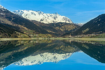 Fototapeta na wymiar Panoramic view of the lake in the mountains. With the village of Resia, Reschen in South Tyrol, Südtirol, Trentino Alto Adige, Italia, Europa