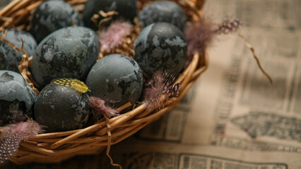 Easter card with a copy of the place for the text. Purple, blue eggs in a basket on a dark newspaper background. Natural dye karkade tea.