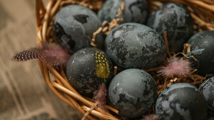 Easter card with a copy of the place for the text. Purple, blue eggs in a basket on a dark newspaper background. Natural dye karkade tea.
