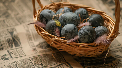 Easter card with a copy of the place for the text. Purple, blue eggs in a basket on a dark newspaper background. Natural dye karkade tea.