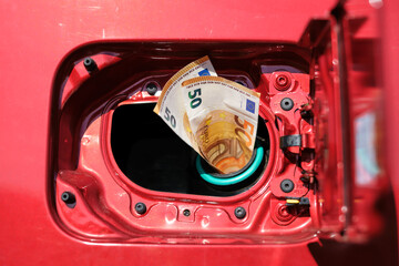 Two fifty euro banknotes sticking out of a car tank, high transportation costs due to rising fuel prices.