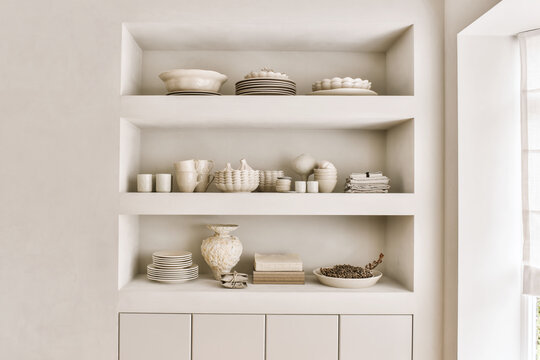 Shelves with ceramic dishware in modern minimalist kitchen