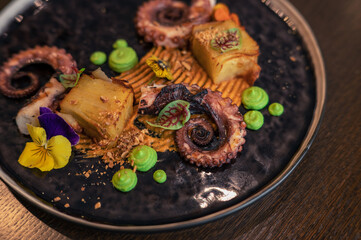 Octopus with potatoes on pea mash decorated with edible flowers
