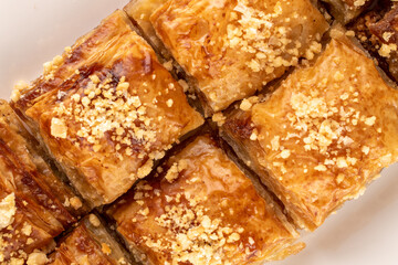 Classic sweet baklava on a white ceramic plate, macro, top view.