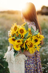 Beautiful woman holding sunflowers in summer evening meadow. Tranquil atmospheric moment in...