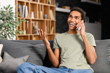 Smiling and positive multiracial guy in casual shirt talking by the smartphone. Cheerful mixed-race...