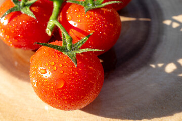 Shallow focus of surface water droplets seen after washing organically grown tomatoes. Seen on a chopping board, soon to be used in a Pizza.