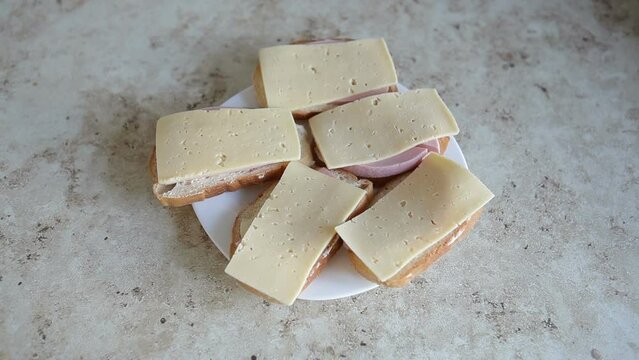 A plate with homemade sandwiches on the table. White bread with boiled sausage and cheese for breakfast.
